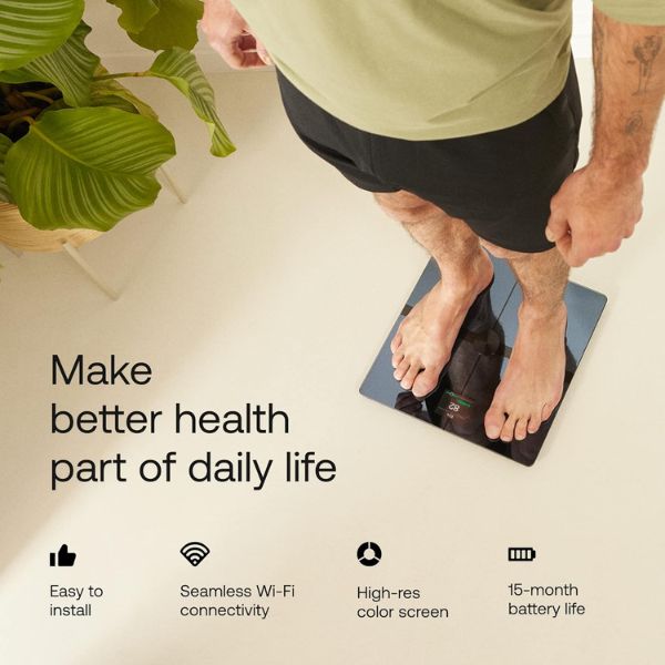 Withings Body Smart scale measuring body fat percentage and body composition metrics on a modern bathroom floor.